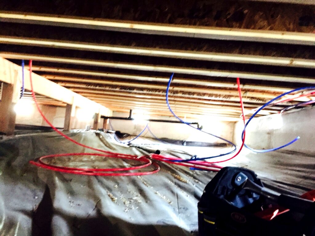 Red and blue PEX water lines installed in a crawlspace